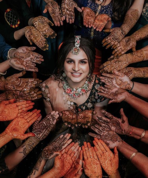 Bride in center with hands with mehndi around her