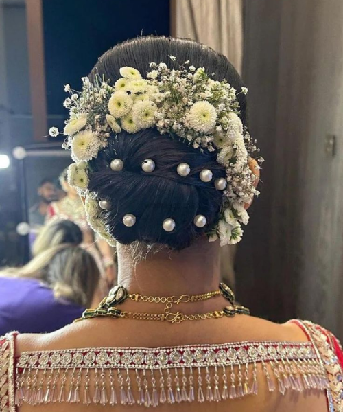 Bun hairdo with pearl pins and fresh flowers around her bun