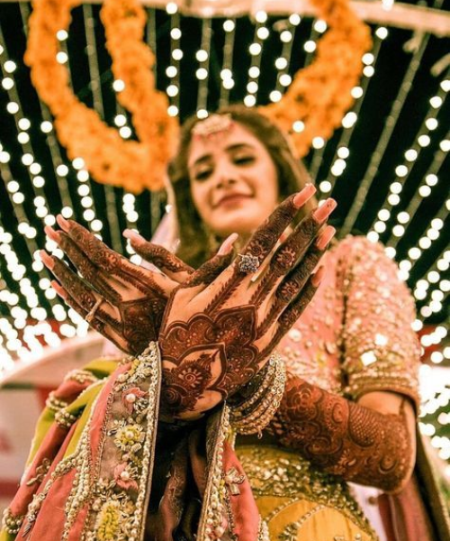 Showing back hand mehndi hands crossed