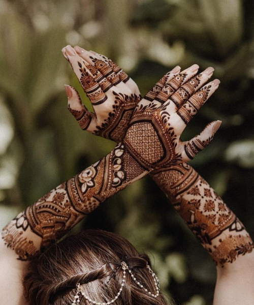 Crossing hands above the hands to show full mehndi