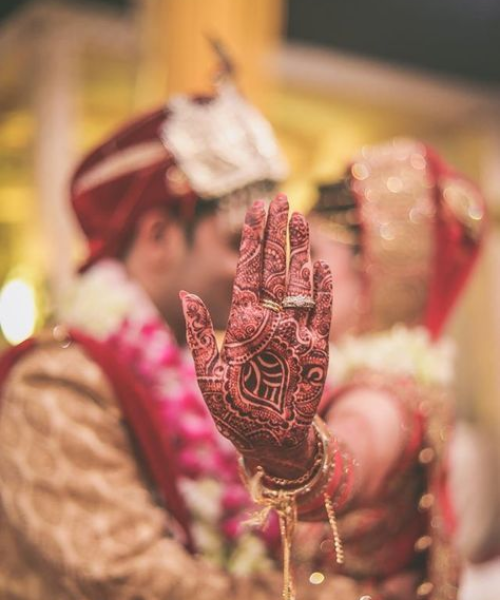 Creative Mehndi Focus Pose with Blurred Couple